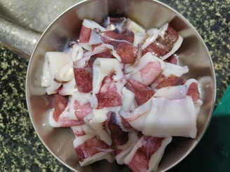 A close-up shot of traditional hand-pounded squid cake being prepared in a rustic kitchen.