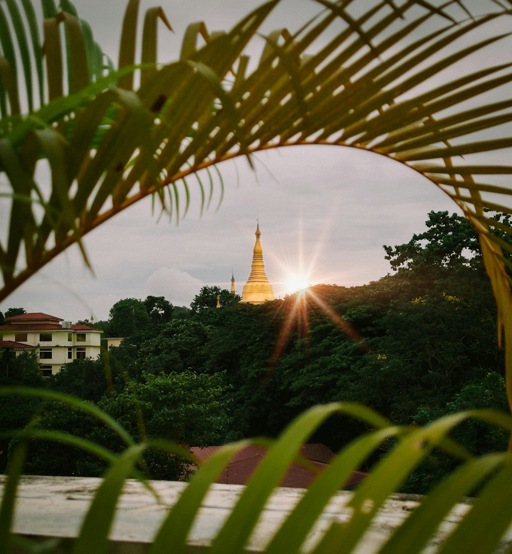 the sun is setting behind a building with a spire