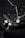 Elegant jewelry pieces, including a gold pendant with a large diamond and matching earrings, displayed on a wet, glossy black stone surface with water droplets.