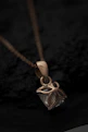 Close-up image of a delicate silver jade pendant glowing softly on a minimalist black background.