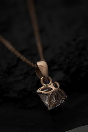 Close-up of a delicate gold necklace resting on a soft velvet cushion, highlighting intricate details.