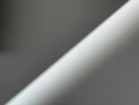 A minimalistic image featuring diagonal lines of light and shadow on a textured surface.