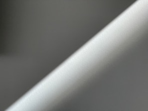 A minimalistic image featuring diagonal lines of light and shadow on a textured surface.