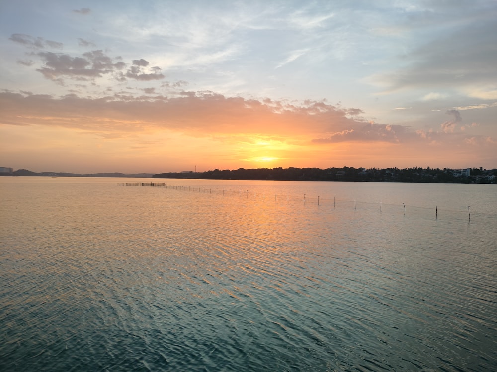 a body of water with a sunset in the background