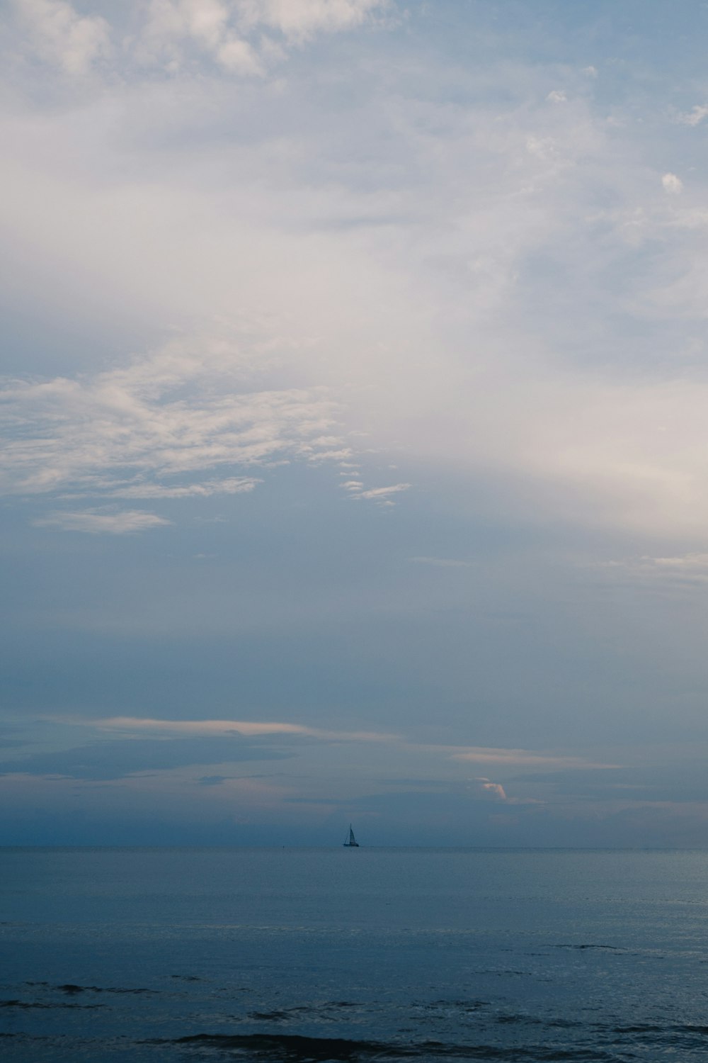 a sailboat is out on the ocean under a cloudy sky