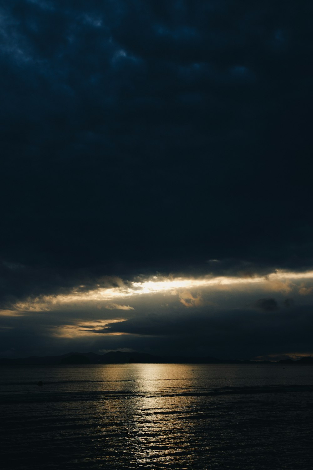 a plane flying over a body of water under a cloudy sky