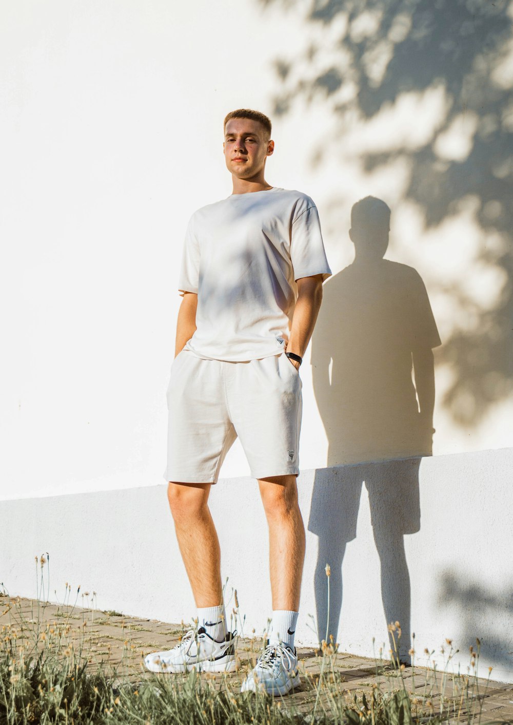 a man standing next to a white wall