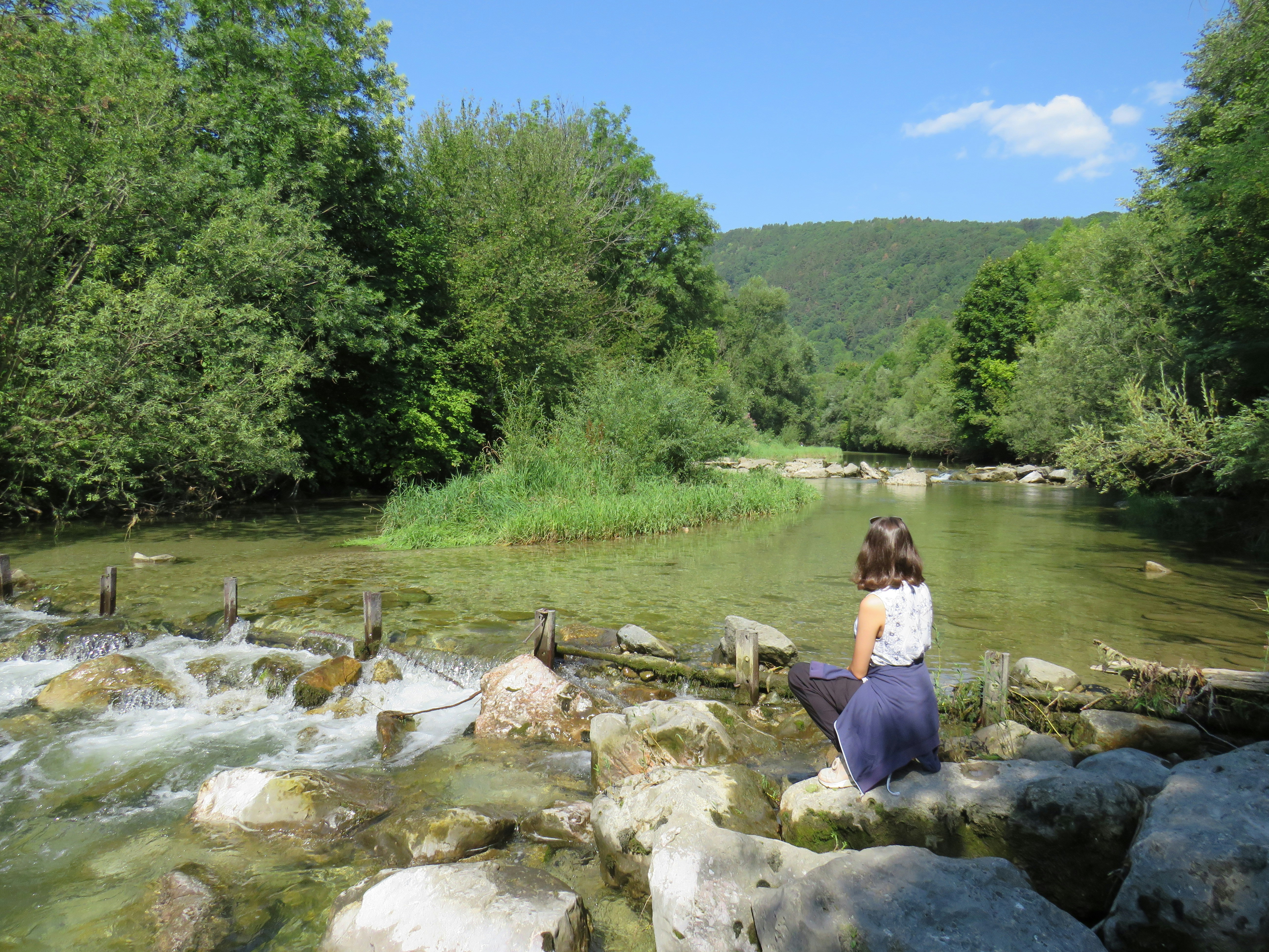 a woman sitting on a rock next to a river