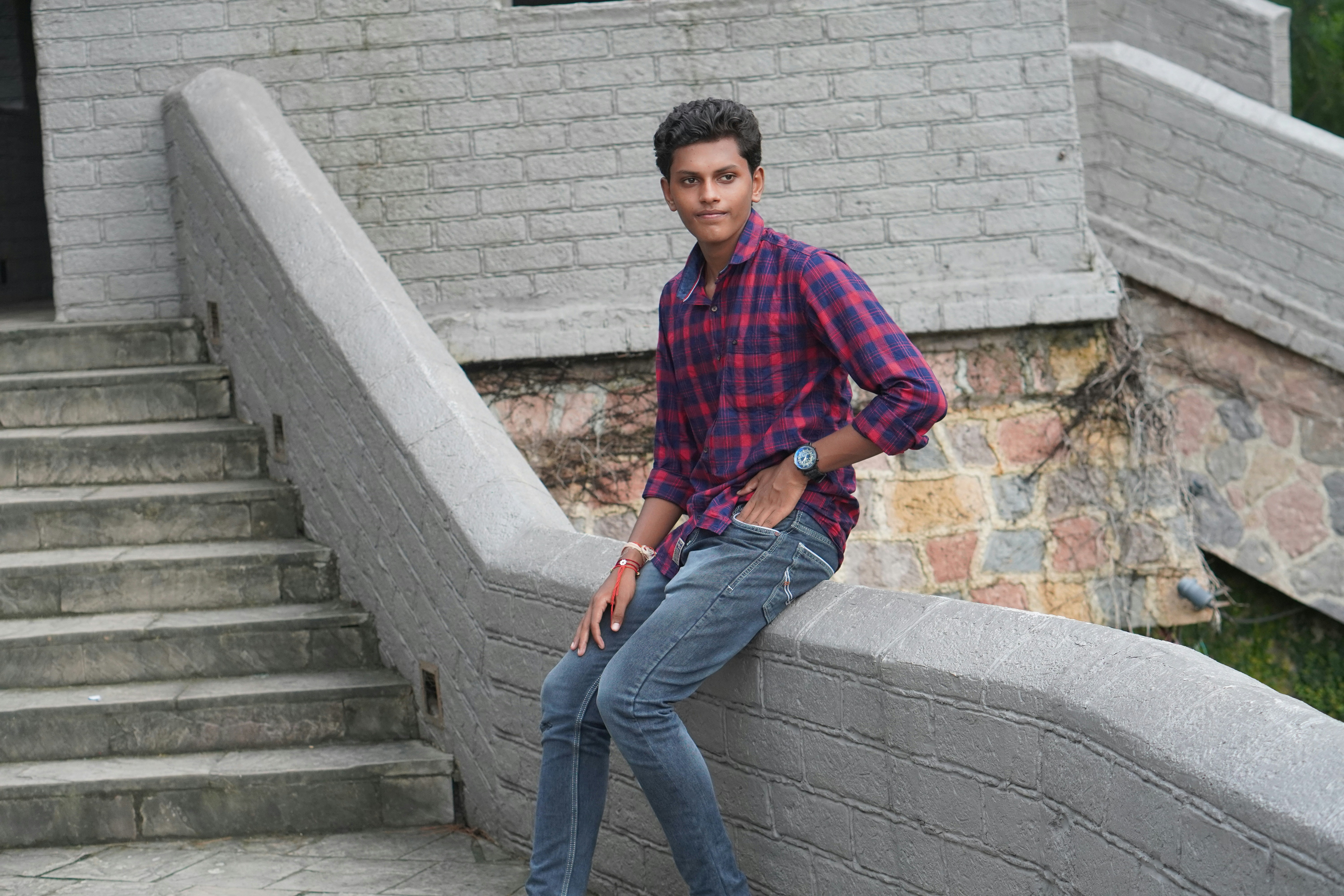 a young man leaning against a stone wall