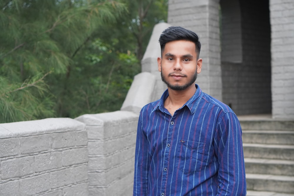 a man standing in front of a stone wall