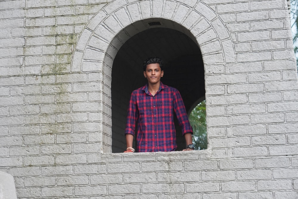 a man standing in a window of a brick building