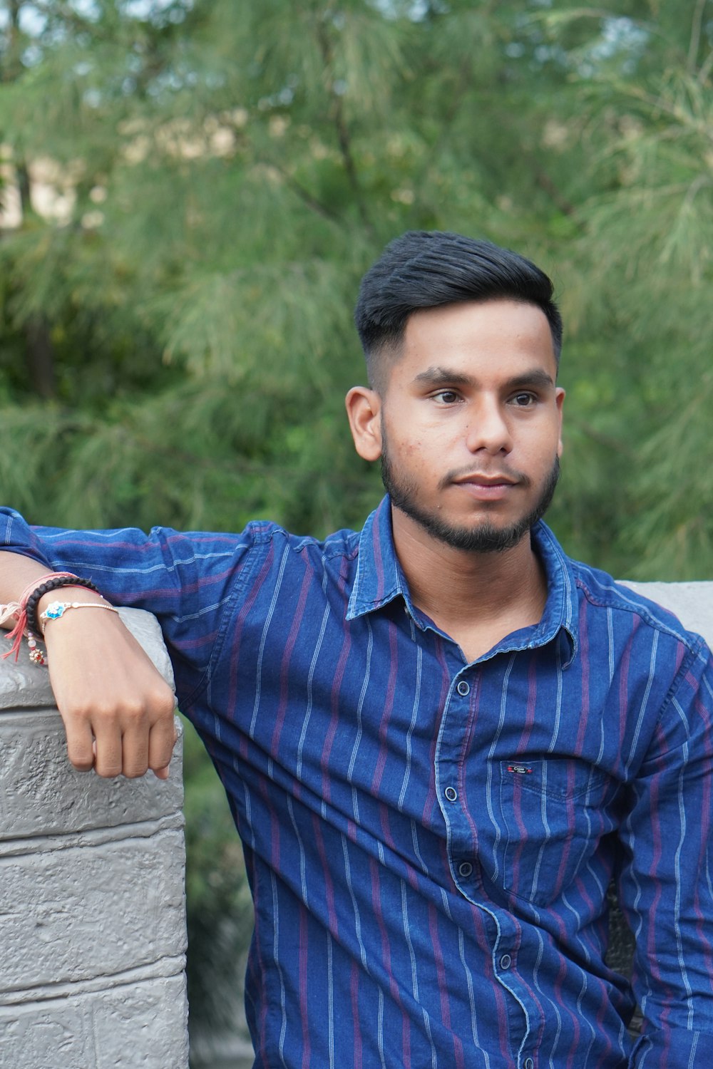 a man in a blue shirt leaning against a wall