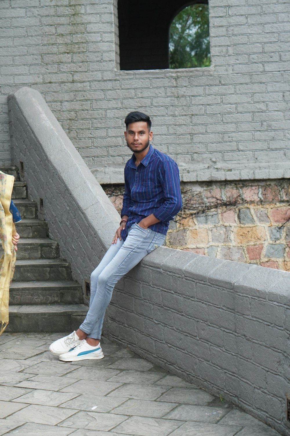 a man sitting on a ledge next to a brick building