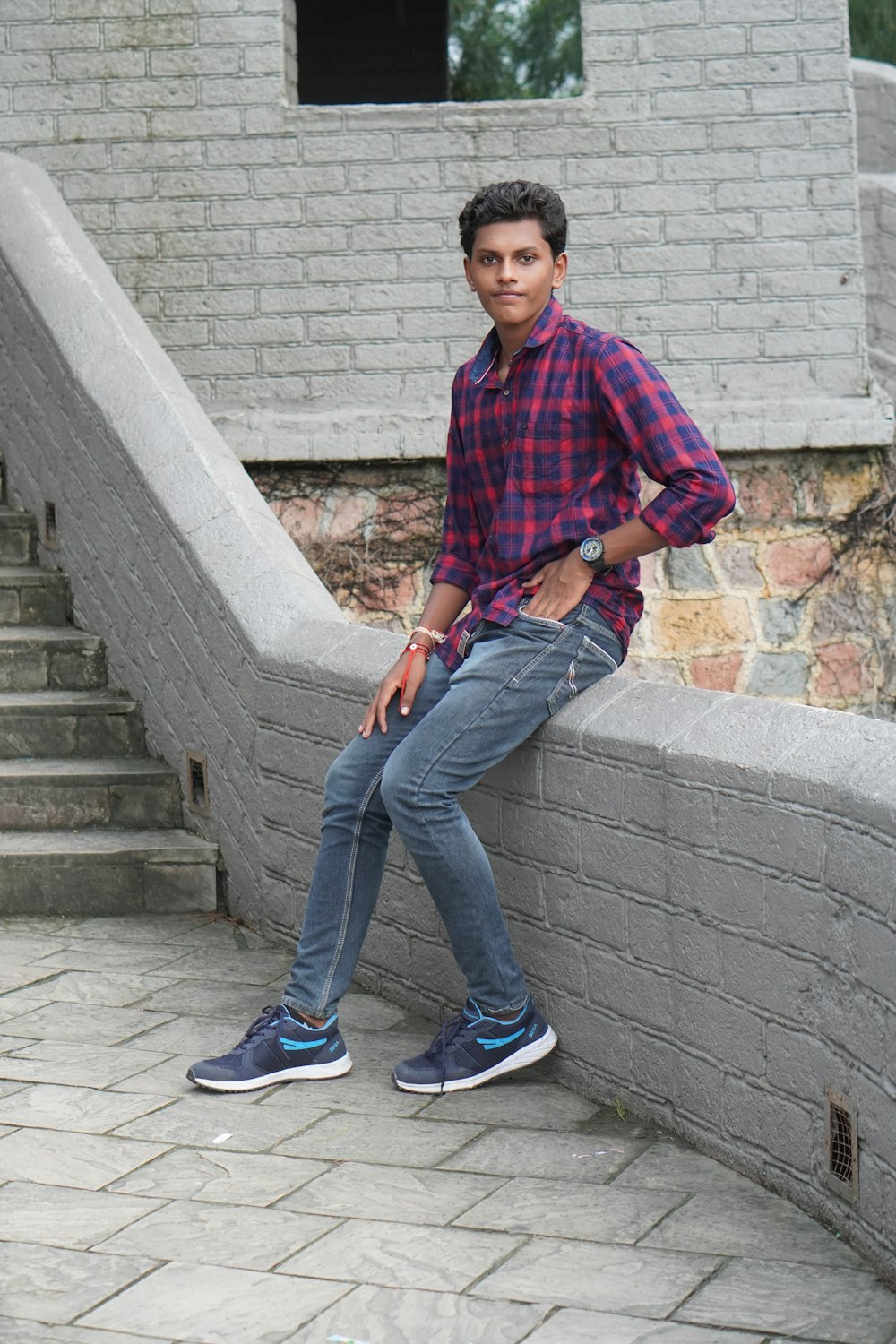 a young man sitting on a ledge next to a brick building