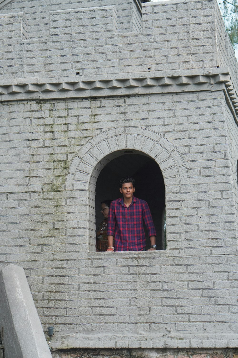 a man standing in a window of a brick building