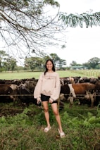 A smiling farmer holding a healthy calf in a green pasture.
