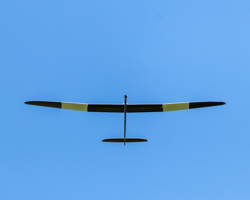 a small airplane flying through a blue sky