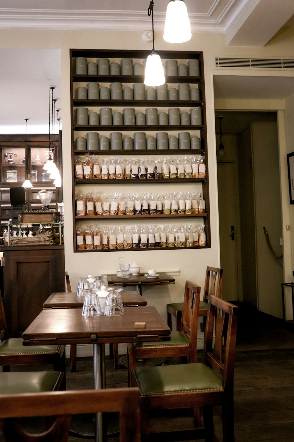 a restaurant with tables and chairs and a shelf filled with jars