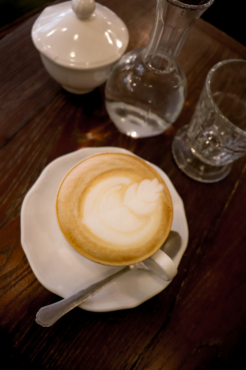 Um cappuccino senta-se sobre um pires sobre uma mesa de madeira