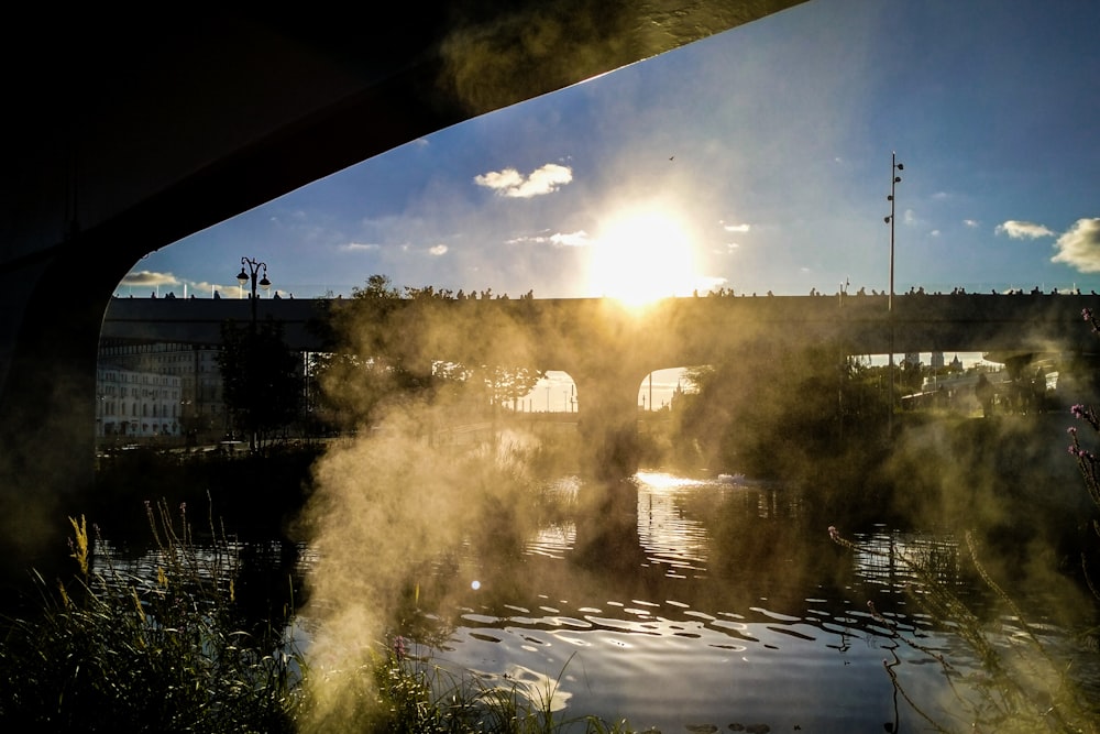 a river with steam rising from it and a bridge in the background