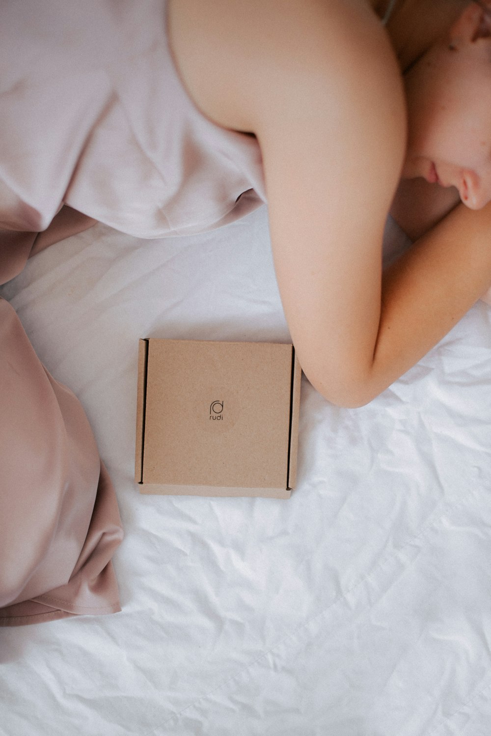 a woman laying in bed next to a box