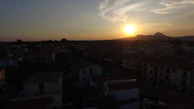 Evening view of the village rooftops glowing under a warm sunset sky, seen from the balcony.