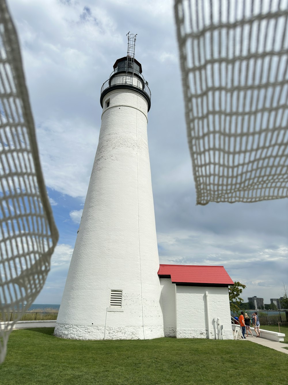 a white lighthouse with a red roof on a cloudy day