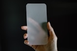 A hand holding a tempered glass screen protector against a blurred background.