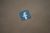 a blue and white facebook logo on a brown surface