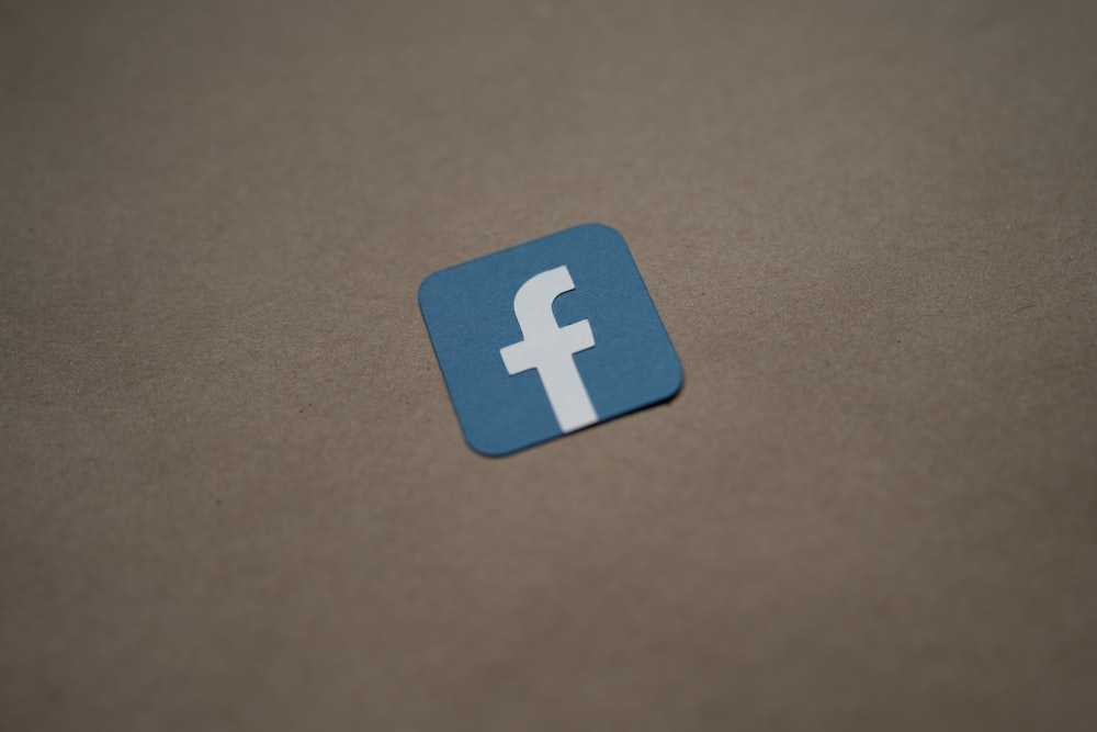 a blue and white facebook logo on a brown surface