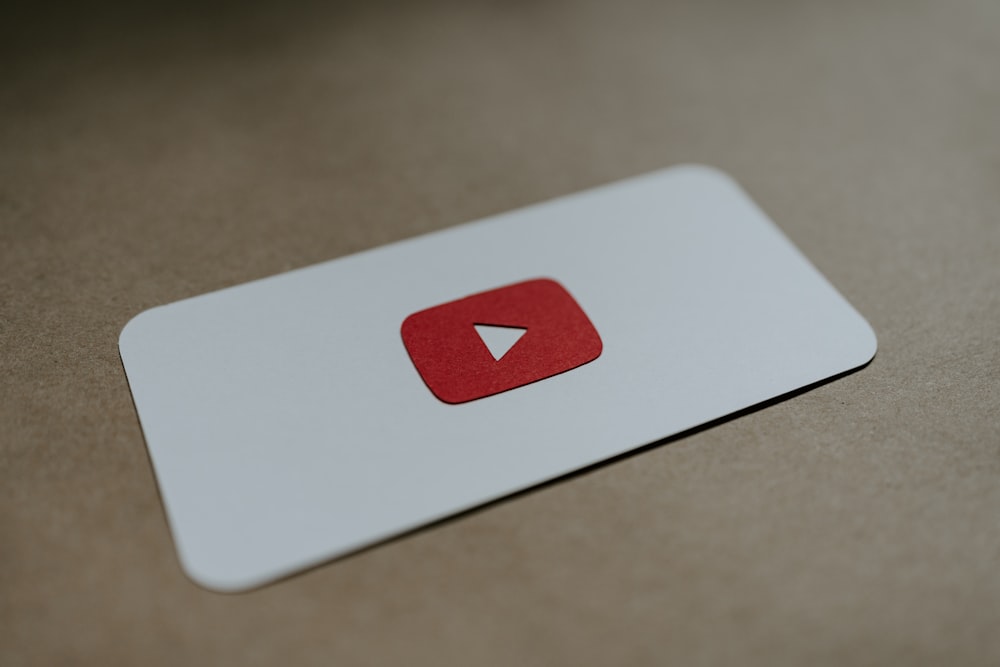 a red and white play button on a white card