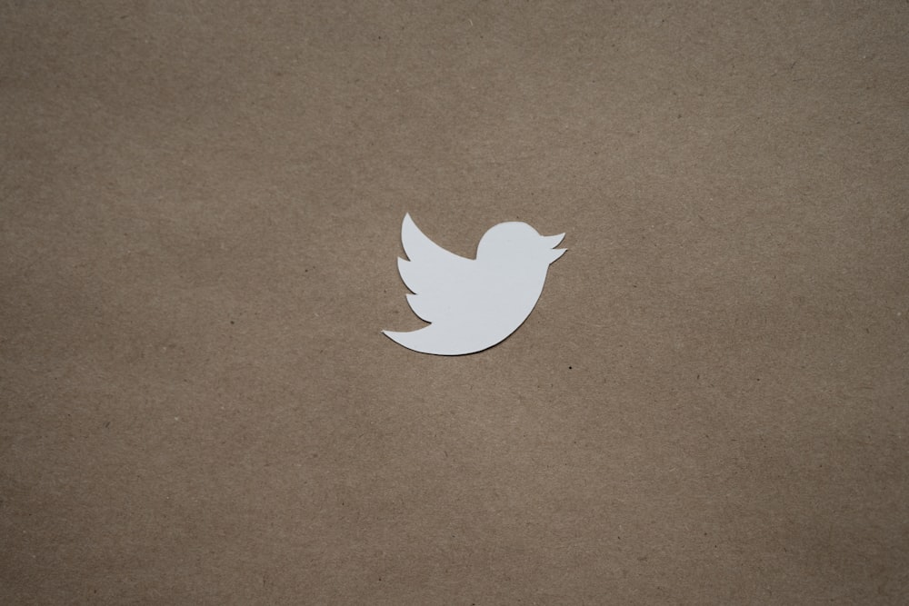 a white paper bird sitting on top of a brown surface