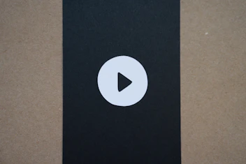 Minimalist icon of a play button over a navy and gold background.