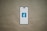 A smartphone is depicted with a white screen displaying a blue logo with the letter 'f', set against a plain brown background.