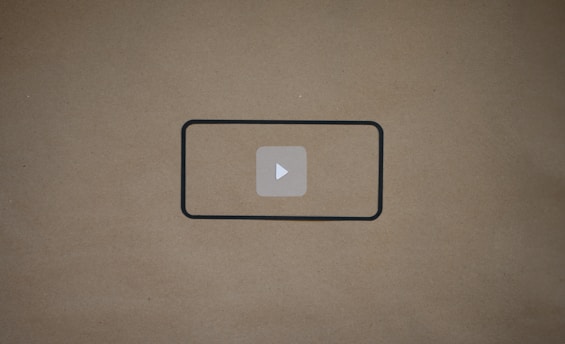 A blank brown background with a black rectangle outline in the center. Inside the outline, there is a light gray play button icon.