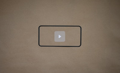 A blank brown background with a black rectangle outline in the center. Inside the outline, there is a light gray play button icon.