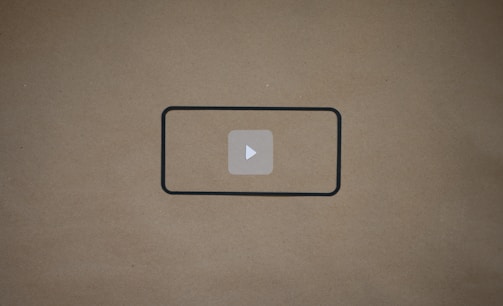 A sleek black background with a vibrant video play button glowing softly in the center.