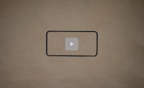 A blank brown background with a black rectangle outline in the center. Inside the outline, there is a light gray play button icon.