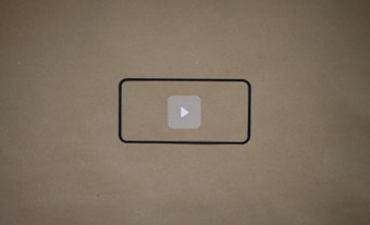 A blank brown background with a black rectangle outline in the center. Inside the outline, there is a light gray play button icon.