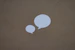 two white speech bubbles sitting on top of a brown surface