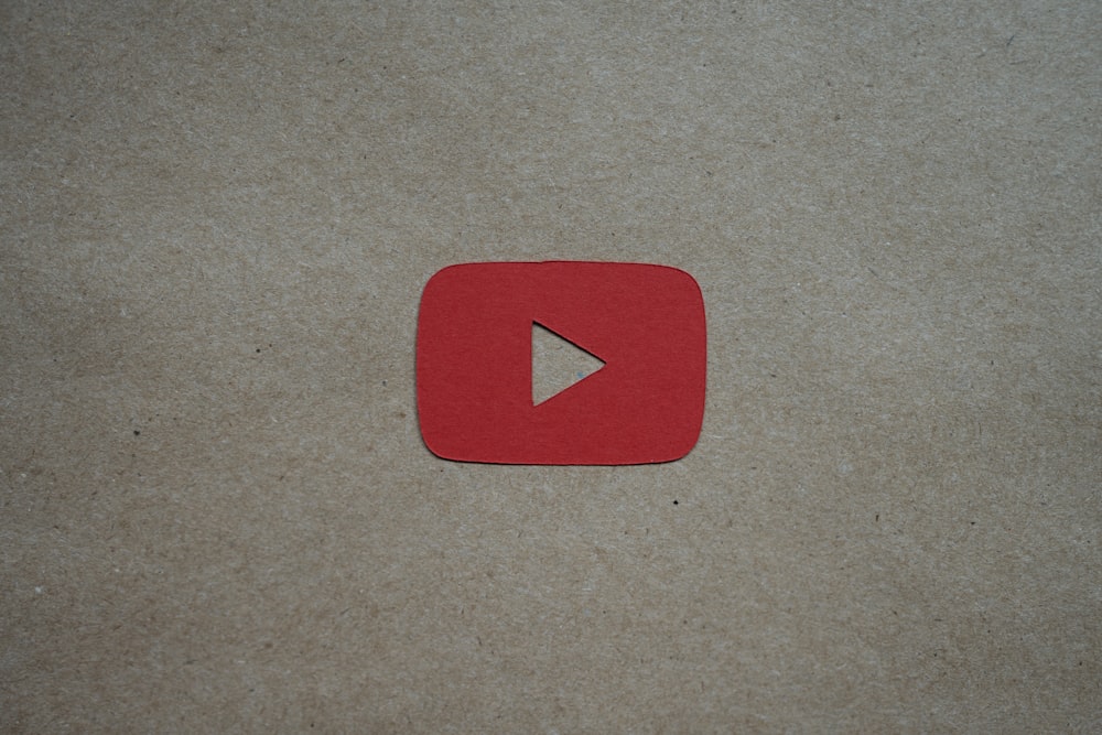 a red play button sitting on top of a piece of paper