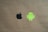Two logos are positioned on a plain brown background. The black apple logo is on the left side, and the green android robot logo is on the right.
