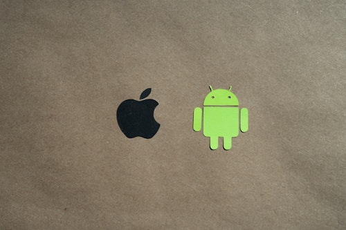 Two logos are positioned on a plain brown background. The black apple logo is on the left side, and the green android robot logo is on the right.