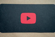 A minimalist YouTube play button illuminated in gold on a dark backdrop.