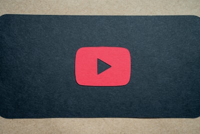 A red play button symbol is centered on a dark background, resembling the YouTube logo.