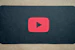 A minimalist YouTube play button illuminated in gold on a dark backdrop.