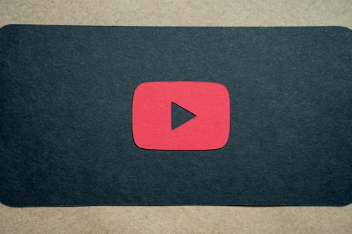A red play button symbol is centered on a dark background, resembling the YouTube logo.