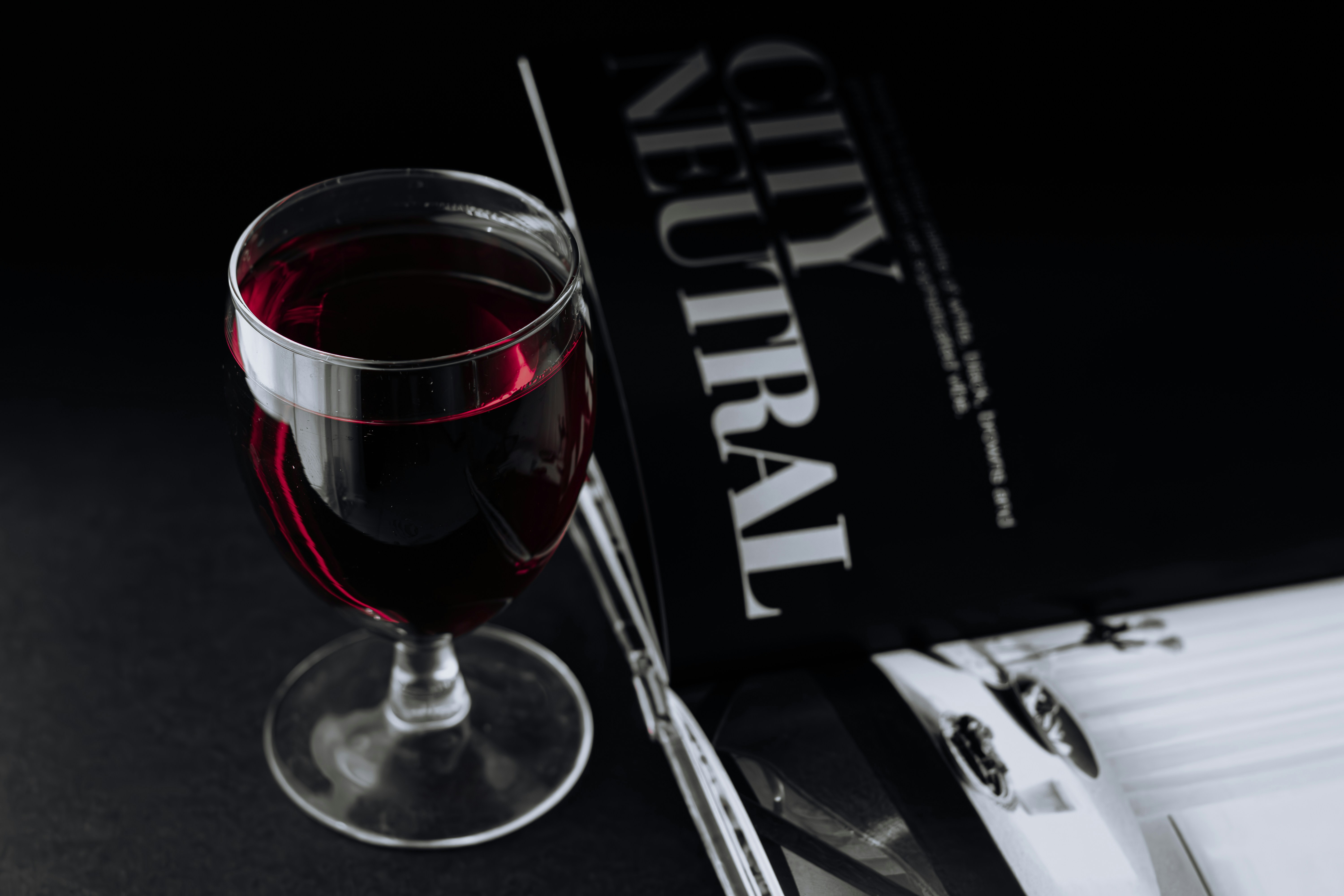a glass of red wine next to a book, 