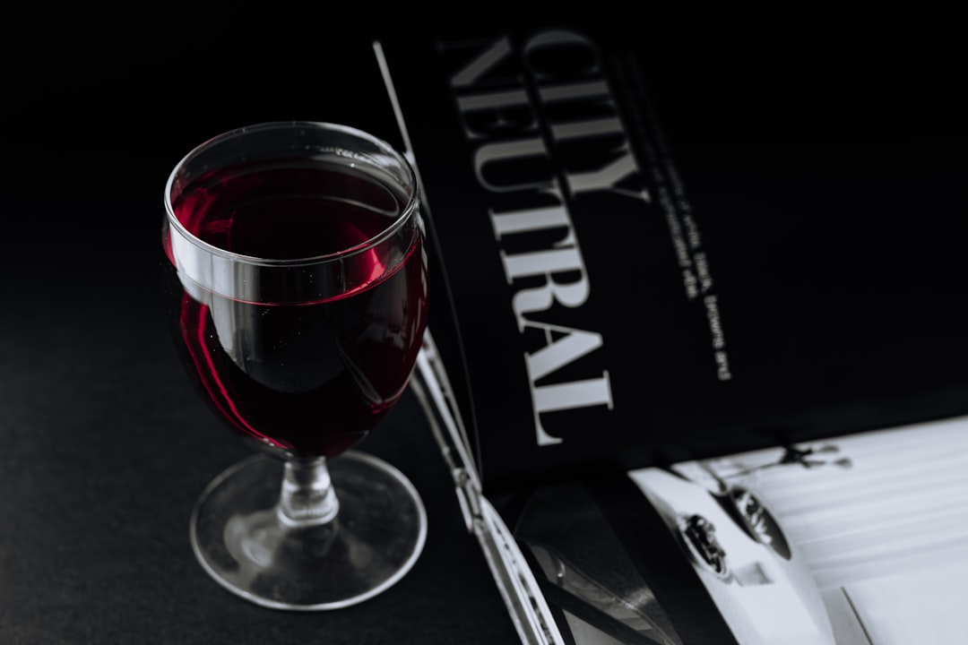 a glass of red wine next to a book,