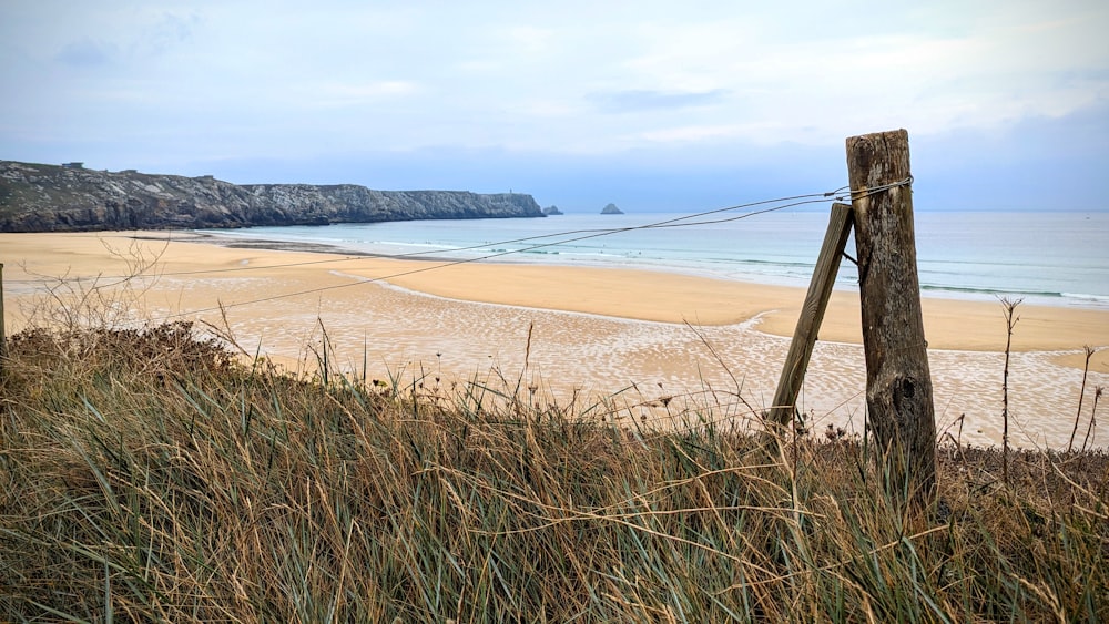 a wooden fence on a beach with a body of water in the background